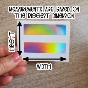 May include: White sticker with two iridescent holographic rectangles. The sticker has the text "Measurements are based on the biggest dimension" at the top and "Height" and "Width" written vertically on the left and horizontally at the bottom.