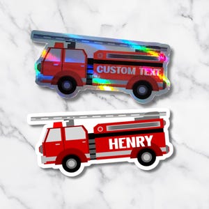 May include: Two red fire truck stickers. One has the text "CUSTOM TEXT" and a holographic finish. The other has the name "HENRY" in white. Both have black wheels and a white ladder.