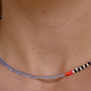 May include: A multi-colored beaded necklace with a mix of light purple, yellow, white, and black beads.