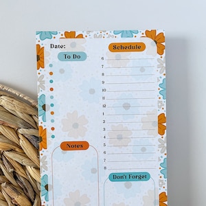 May include: A white notepad with a floral design in shades of blue, orange, and white. The notepad has sections for "To Do", "Schedule", "Notes", and "Don't Forget".