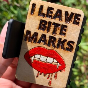 Może przedstawiać: Drewniana spinka do włosów z grafiką czerwonych i białych ust wampira i tekstem "I Leave Bite Marks".
