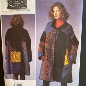 May include: A Vogue pattern for a coat designed by Koos van den Akker. The pattern features a long coat with colour-blocked panels in blue, black, and orange. The front of the pattern shows a woman wearing the coat. The pattern number is V1377.