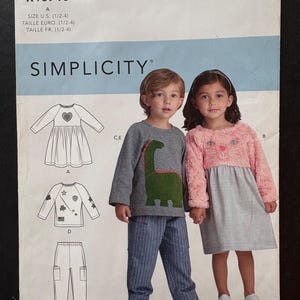 May include: Simplicity sewing pattern R10710 featuring children's clothing designs. The pattern includes illustrations of a dress, a top with star and shamrock details, and pants. The size range is 1/2-4.