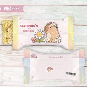 K&ouml;nnte beinhalten: Ein rosa-gelber S&uuml;&szlig;igkeiten-Wrapper mit einem Cartoon-Capybara, das eine Blumenkrone tr&auml;gt. Der Wrapper lautet "Madison's 8th Birthday" und "Thank you for".