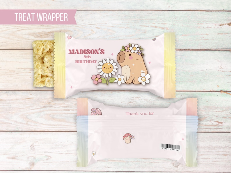 K&ouml;nnte beinhalten: Ein rosa-gelber S&uuml;&szlig;igkeiten-Wrapper mit einem Cartoon-Capybara, das eine Blumenkrone tr&auml;gt. Der Wrapper lautet "Madison's 8th Birthday" und "Thank you for".