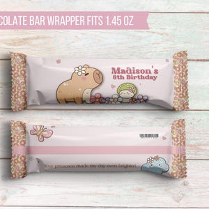 K&ouml;nnte beinhalten: Ein rosa-wei&szlig;er Schokoladenriegel-Wrapper mit einem Cartoon-Capybara- und Pilz-Design. Der Wrapper lautet "Madison's 8th Birthday" und "Your presence made my day even brighter!"