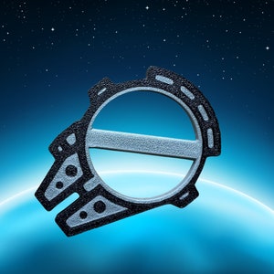 May include: A black and silver spaceship-shaped cookie cutter against a blue and black starry night background.