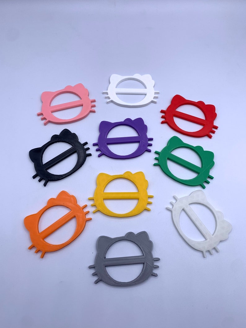 May include: Ten colorful plastic cat-shaped belt buckles in various colors including black, white, pink, red, purple, yellow, orange, green, and gray.