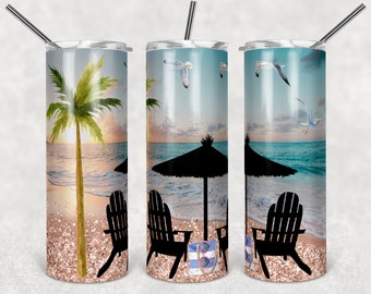 May include: Three stainless steel tumblers with a beach scene design. The tumblers feature a palm tree, beach chairs, an umbrella, and seagulls against a blue sky and ocean background. The beach is covered in pink glitter.