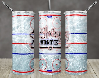 May include: A white tumbler with a blue and red hockey rink design. The text "Hockey Auntie" is printed on the tumbler.