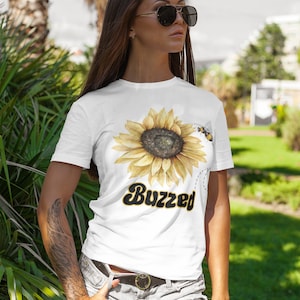 May include: White t-shirt with a yellow sunflower and a bee graphic. The text "Buzzed" is printed in black below the sunflower.