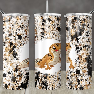 May include: Three stainless steel tumblers with a white background and a black and brown splatter pattern. The centre tumbler features a cartoon gecko with a white background.