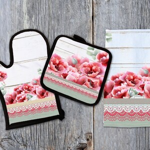 May include: A set of three kitchen accessories featuring a floral design with pink poppies on a white woodgrain background. The set includes a pot holder, oven mitt, and tea towel. Each item has a lace trim and a green and white stripe.