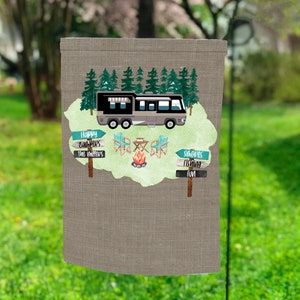 Può includere: Una bandiera da giardino in tela marrone e beige con un camper grigio, alberi verdi e una scena di falò. La bandiera ha il testo "Happy Campfires", "The Millers", "Smores", "Fishing" e "Fun".