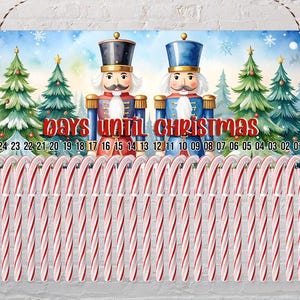 May include: A Christmas countdown sign featuring two nutcracker figures, Christmas trees, and candy canes. The sign reads "Days Until Christmas" with numbers counting down from 24 to 01. The background is a winter scene with snowflakes.