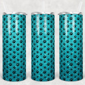 May include: Three tall, insulated tumblers with lids and straws. The tumblers have a teal glitter background with a pattern of black paw prints. The design is repeated on each tumbler, creating a cohesive set.