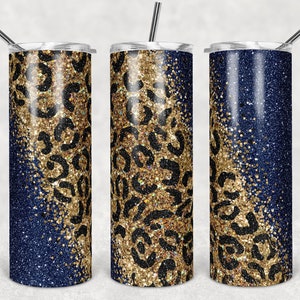 Pode incluir: Três copos de aço inoxidável com tampas e canudos. Os copos são decorados com um fundo de glitter azul e um design de estampa de leopardo de glitter dourado.