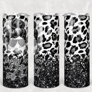 May include: Three stainless steel tumblers with a black and white leopard print design. The tumbler on the left has a black and white illustration of a woman with a messy bun and sunglasses. The text "Messy bun and getting stuff done" is printed on the tumbler. The tumblers have a black glitter design at the bottom.