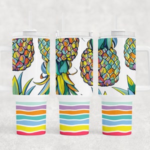 May include: Three white stainless steel tumblers with a colorful pineapple pattern and rainbow stripes. The tumblers have a handle and a lid.