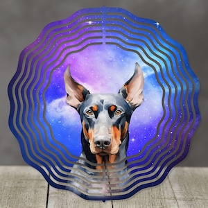 May include: A metal wind spinner with a circular design featuring a Doberman Pinscher dog's head against a galaxy-themed background with blue, purple, and white colors.