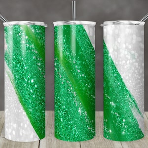 Puede incluir: Tres vasos de acero inoxidable con un diseño de purpurina verde y blanca. Los vasos tienen una franja diagonal de purpurina verde sobre un fondo blanco.