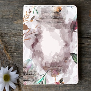 May include: A white leather notebook cover with a watercolor floral design. The design features pink, purple, green, and brown flowers and leaves on a white background with a woodgrain pattern.