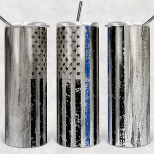Puede incluir: Tres vasos de acero inoxidable con un diseño de veta de madera desgastada. Los vasos presentan un diseño de bandera estadounidense con una fina línea azul que recorre el centro de la bandera.