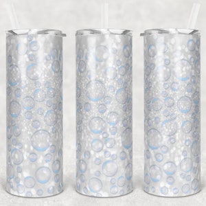 May include: Three stainless steel tumblers with a white and blue glitter pattern. The tumblers have a silver finish and a white lid with a straw.