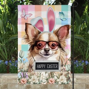 Puede incluir: Un chihuahua con orejas de conejo rosas y gafas de sol con un cartel que dice "Feliz Pascua" frente a un fondo a cuadros de colores con flores.