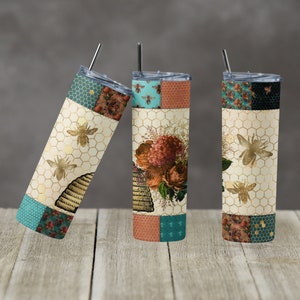 May include: Three stainless steel tumblers with a patchwork design featuring bees, honeycomb, and floral patterns. The tumblers are teal, brown, and black with gold accents.