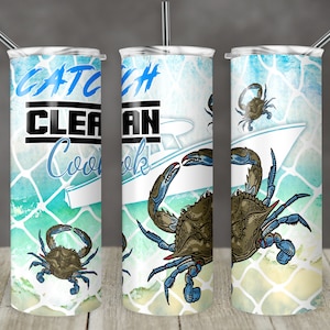 Könnte beinhalten: Ein weißer Becher mit einem blauen und grünen Aquarelldesign, das einen Krebs und ein Boot zeigt. Der Text "Catch Clean Cook" ist auf den Becher gedruckt.