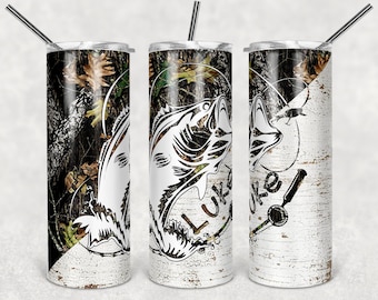 May include: A stainless steel tumbler with a camouflage and wood grain design. The tumbler features a white silhouette of a fish with the word "Luke" written on it.