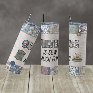 May include: Three stainless steel tumblers with a patchwork design and the text "Quilting is sew much fun!" printed on them. The tumblers are on a wooden surface.