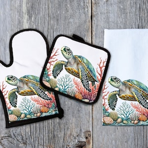 May include: Set of three kitchen textiles featuring a green sea turtle swimming through coral reefs. The set includes a potholder, oven mitt, and tea towel.