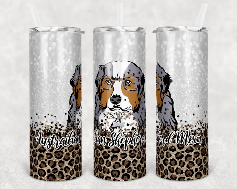 May include: Three stainless steel tumblers with a silver glitter background and a leopard print design. The center tumbler features a cartoon Australian Shepherd dog wearing glasses and the text "Australian Shepherd Mom".