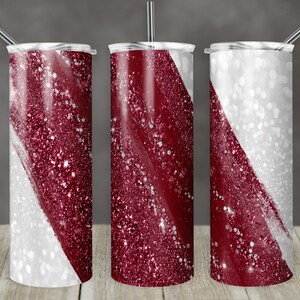 Puede incluir: Tres vasos de acero inoxidable con tapas y pajitas. Cada vaso presenta un diseño de una franja diagonal de purpurina burdeos brillante sobre un fondo blanco. Los vasos son cilíndricos y están diseñados para bebidas.