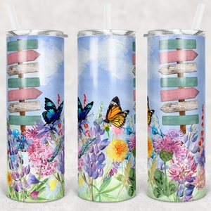 May include: A stainless steel tumbler with a watercolor design of butterflies and flowers. The tumbler features a stack of wooden signs with pink and green paint.