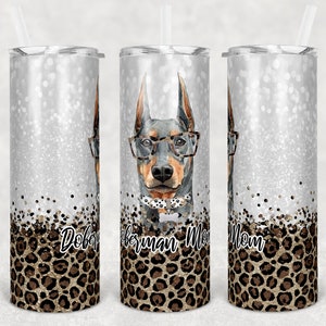 May include: Three stainless steel tumblers with a silver glitter background and a leopard print design. The tumblers feature a Doberman Pinscher wearing glasses and a bow tie. The text "Doberman Mom" is printed on the tumblers.