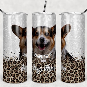 May include: A stainless steel tumbler with a white glitter background and a brown and black corgi dog image. The tumbler has a leopard print design with gold glitter accents and the text "Corgi Mom" on the front.