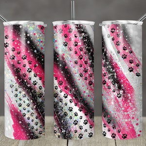 Op de afbeelding: Drie roestvrijstalen bekers met een roze, zwart en wit glitterontwerp. Het ontwerp bevat zwarte poot afdrukken en roze en witte penseelstreken.
