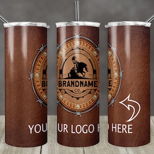 May include: A brown leather-textured stainless steel tumbler with a silver metal band and a logo that says "BRANDNAME CO. PERFORMANCE HORSES" with a silhouette of a cowboy riding a horse. The tumbler has a straw and is on a wooden surface.