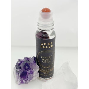 May include: A black roller bottle with a gold label that reads "Aries Ruler Zodiac Moon Child" and "Essential Oil Blend Incense, Rose, Sandalwood, Heliotrope & FCO. Net Wt. 10 ml."