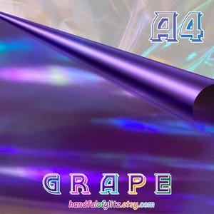 Pode incluir: Um rolo de vinil roxo iridescente com a palavra "GRAPE" em letras coloridas com contorno. O texto "A4" está em uma fonte azul e branca com contorno. O nome da loja Etsy "handfulofglitz.etsy.com" também é visível.
