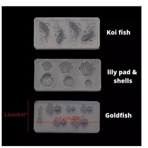 May include: Three silicone molds for crafting. The top mold features four koi fish designs. The middle mold has three lily pad and shell designs. The bottom mold has four goldfish designs. The molds are labeled "Koi fish", "lily pad & shells", and "Goldfish". The molds measure 1.2 inches by 4.2 inches.