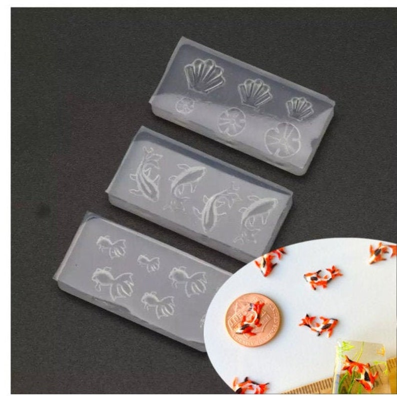 May include: Three clear silicone molds for resin casting. The molds feature different designs: seashells, flowers, and koi fish. The molds are perfect for creating unique jewelry, home decor, and other crafts.