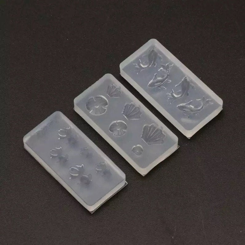 May include: Three clear silicone molds for crafting. The molds feature different designs: one with seashells, one with flowers, and one with fish.