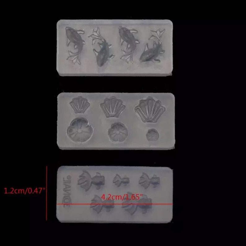 May include: Three silicone molds for crafting. The first mold has four fish designs. The second mold has three seashell designs and three flower designs. The third mold has three bow designs and three fish designs. The molds are 4.2 cm by 1.2 cm.