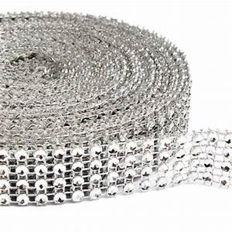 Puede incluir: Una bobina de ribete de strass plateado, con peque&ntilde;os strass redondos dispuestos en una l&iacute;nea continua. El ribete es perfecto para agregar brillo y glamour a las manualidades, la ropa y la decoraci&oacute;n del hogar.