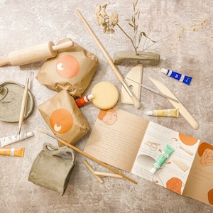May include: A pottery tool kit with various supplies for creating clay art. Includes a wooden rolling pin, paint tubes, brushes, a sponge, and a booklet with instructions. The kit is designed for beginners and includes all the necessary tools.
