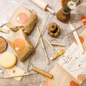 May include: A pottery tool kit with various supplies. Includes paint tubes, brushes, clay, a rolling pin, and a tool kit guide. The kit contains clay, tools, and instructions for creating pottery. The kit is designed for therapeutic and rewarding creative experiences.